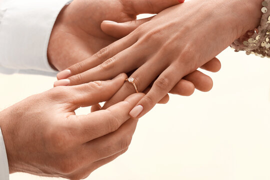 Man putting engagement ring on woman's finger, closeup