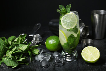 Glass of cold mojito and ingredients on dark background