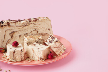 Plate with pieces of tasty marble halva on pink background
