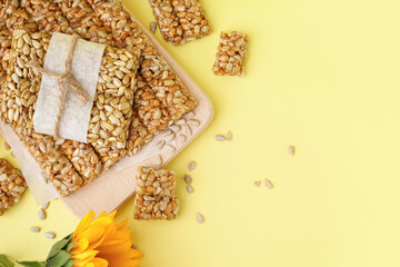 Tasty kozinaki and seeds on pale yellow background