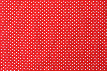 Bright red fabric material with a white polkadot pattern. Backgrounds.