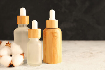 Bottles of essential oil and cotton flowers on light table