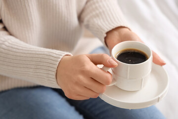 Woman holding saucer with cup of coffee, closeup