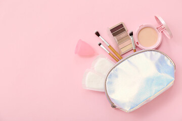 Lady's cosmetic bag with menstrual cup, pads and makeup products on pink background