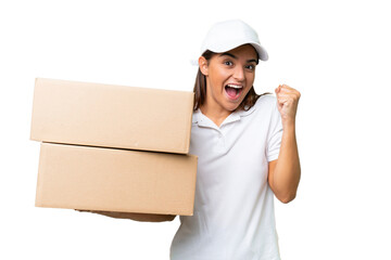 Delivery caucasian woman holding boxes isolated on green chroma background celebrating a victory in winner position