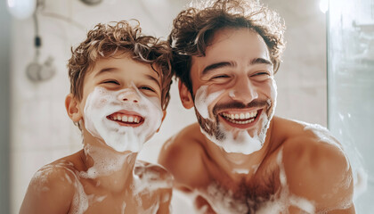 African American father and son in bathroom looking together in their reflection in mirror and cheerfully smiling while they apply shaving foam on their faces. Warm father and son relations concept.
