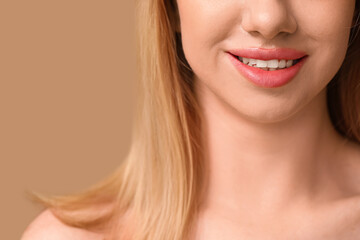 Smiling young woman with beautiful lips on brown background, closeup