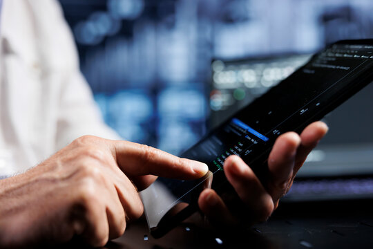 System administrator coding in data center using javascript language, close up. Competent manager updating software on server rigs on tablet terminal, ensuring optimal performance and security