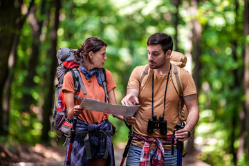 Hiker couple in the forest using map