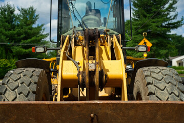 Face to face with a front end loader sitting idle in a street construction project, with focus on...