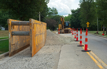 A trench box for laying pipe in a water line replacement and backhoe in a road construction zone