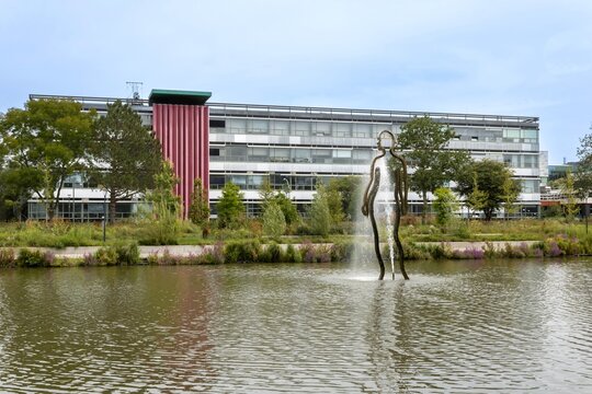 Groningen, Netherlands - August 1, 2024: The building of Association of Applied Physics T.F.V. 'Professor Francken' and pond with fountain The Changing Same in the University of Groningen campus