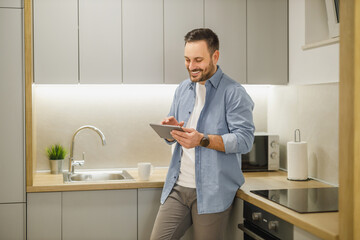 Man Drinking Coffee and Using Tablet in Kitchen