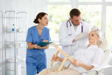 Obraz premium Skilled male beautician giving consultation to woman patient with mirror in aesthetic clinic