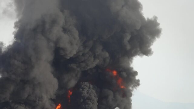Chemical solvent plant burns down with a black column of toxic smoke.