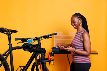 Picture of young african american female arranging professional equipment for bike maintenance. Sporty black woman selecting and preparing necessary expert tools for servicing damaged bicycle.