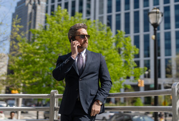 Business communication. Business man having phone call outdoor. Businessman using phone. Man phone conversation in suit. Middle aged Hispanic businessman with phone. Feedback loop