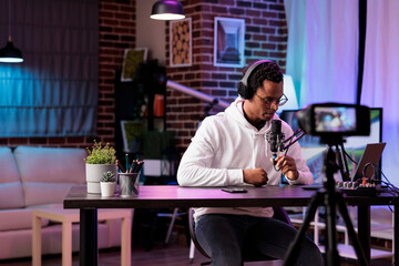 Vlogger recording internet show using modern camera checking comments left by fans. Man filming content for online vlog, reading remarks left by supporters on his channel videos