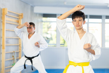 Sportive teen boy wearing kimono training karate techniques during workout session