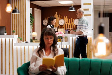 Arrival at hotel reception, employee verifies identification documents ensuring smooth check-in process for elderly male tourist. Passport of old man is held and checked by concierge for booking.