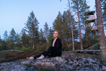 Fototapeta premium blonde woman hiking in the forest in Rovaniemi Finland Lapland, on a white night in summer with sunset