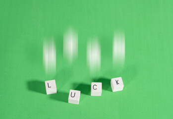 Dice forming the word Luck in English on a green background with a halo of movement. Gambling addiction.