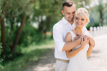 Obraz premium Happy Embrace of Newlywed Couple in Sunlit Outdoor Setting