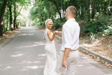 Happy Bride and Groom Strolling Outdoors on Wedding Day in Beautiful Forest Setting