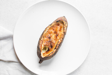 Overhead view of sweet potato crème brûlée on a white plate, top view of a sweet potato filled with creme brulee
