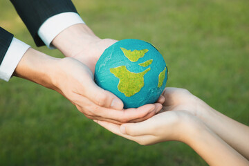 Businessman hand giving Earth globe to little boy as Earth day concept as corporate social responsible to contribute greener environmental protection for sustainable future generation. Gyre