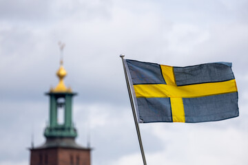 The swedish flag in front of the City hall in the capital of Stockholm, flag in focus.