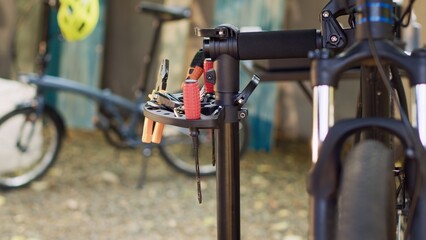 Outdoor bicycle repair and maintenance with professional tools placed on repair-stand. The lens capturing various specialized tools prepared for bike fixing and servicing in home yard.