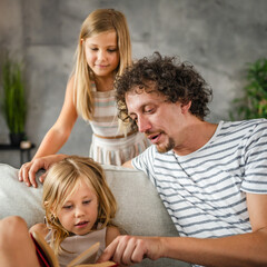 Young girl caucasian child read a book to her father and older sister