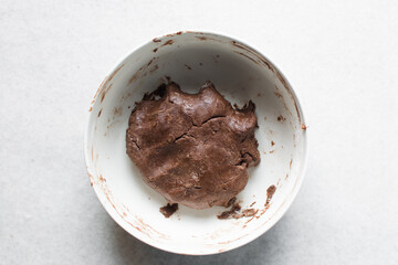 Overhead view of chocolate cookie dough in a white ceramic bowl, top view of dark chocolate sugar cookie dough in a white mxing bowl,  process of making chocolate sugar cookies