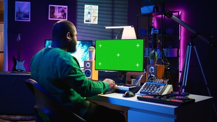 Songwriter operates on synthesizer piano keys next to isolated display, composing new music with...
