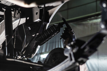 The master sprays an anti-corrosion compound on the bottom of the car. 