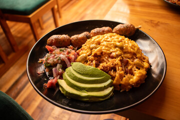 Moro rice with lentils and cheese, served with Cuencano chorizo, accompanied by avocado slices and fresh lettuce