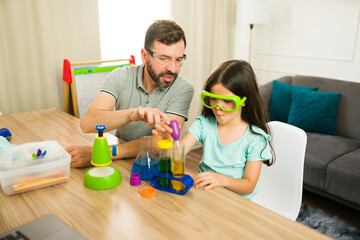 Father teaching his daughter science at home using test tubes and a pipette