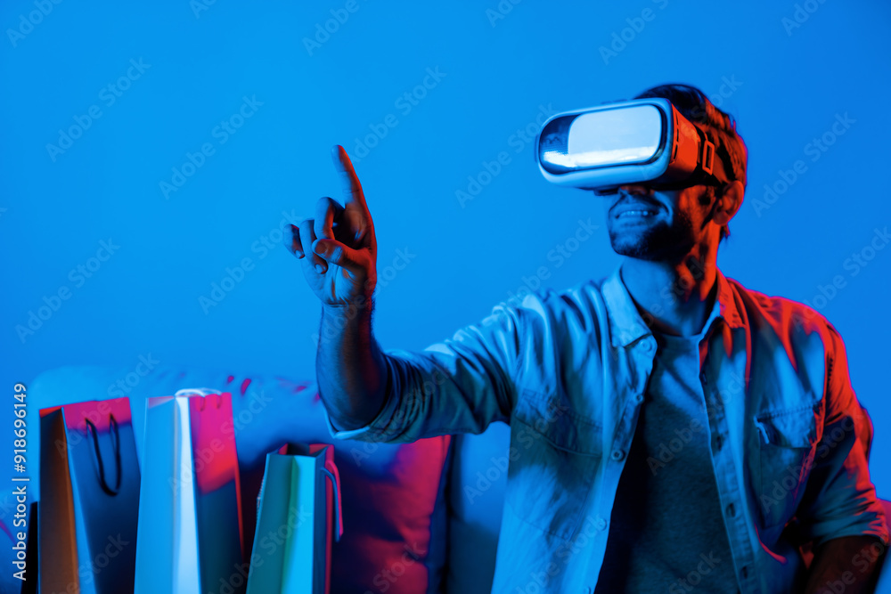 Wall mural caucasian man with vr glass posing pointing finger while sitting at sofa with shopping bags. person 