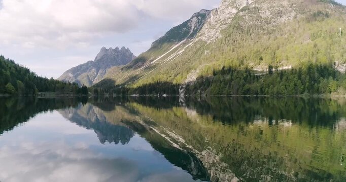 Aerial drone view of Lago del Predil in Tarvisio. Panoramic from above with the view of the Alps in background, trekking and summer holidays. Perfect reflection on the surface creates a human face.