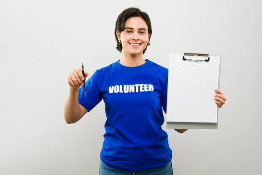 Female volunteer in blue t-shirt with clipboard and pen asking more people to join her cause