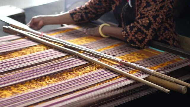 An Indonesian woman weaving traditional flores fabric. Traditional weaving cotton in Indonesia. Making tenun ikat.	