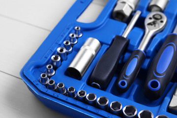 Auto mechanic's tools in plastic box on white wooden table, closeup