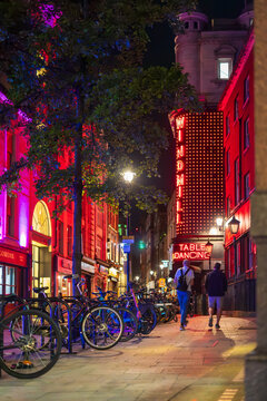 A vibrant night scene in Soho, London, showcasing the colorful neon lights of the Windmill club