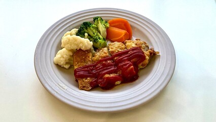 ケチャップがかかったポークソテーと添えられた野菜