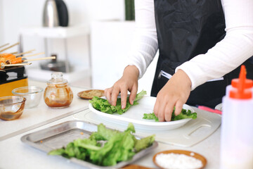 Woman making salad, put the lettuce leaves into a plate at the kitchen