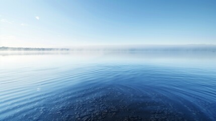 Fototapeta premium A calm lake with a misty morning fog, the water surface like glass reflecting the early light.
