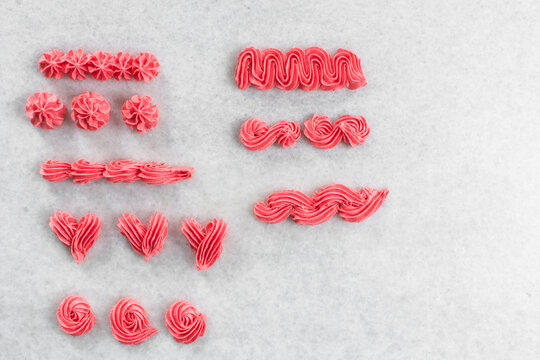 Pink buttercream piped on a granite countertop, buttercream piped using a piping tip on a white countertop