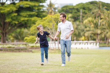 Fototapeta premium Man piggyback his son on a shoulder and walking around the park.