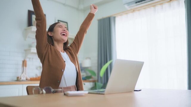 Funny euphoric young asian woman celebrating winning or getting ecommerce shopping offer on computer laptop. Excited happy girl winner looking at notebook celebrating success